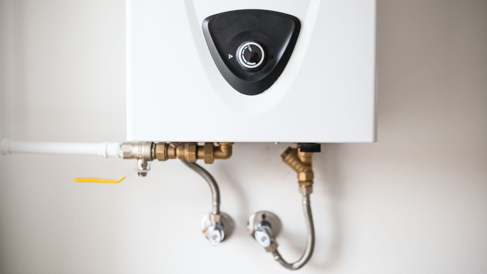 White water heater with black control panel and brass plumbing connections