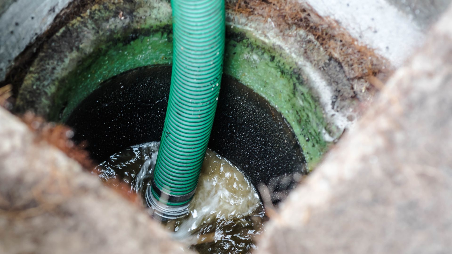 Green corrugated pipe through rocky surface with water and moss